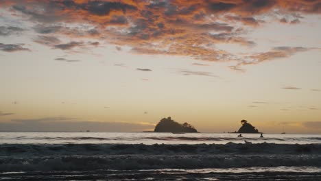 Menschen-Am-Strand-Von-Costa-Rica-Mit-Rauen-Wellen-Während-Des-Sonnenuntergangs-In-Guanacaste,-Mittelamerika