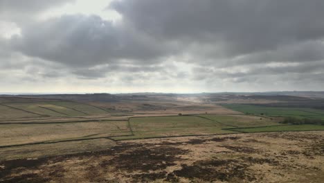Cinematic-aerial-footage-revealing-a-beautiful,-open-expanse-of-moorland-with-dramatic-clouds-on-the-horizon