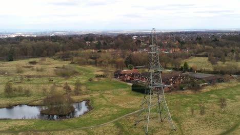 Flying-orbiting-shot-Electricity-distribution-power-pylon-overlooking-British-parkland-countryside