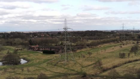Flying-towards-Electricity-distribution-power-pylon-overlooking-British-parkland-countryside