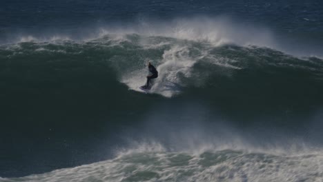 Surfer-surfing-huge-waves-of-Nazare,-Portugal,-360-trick-or-stunt,-extreme-adrenaline-dangerous-sport-in-slow-motion