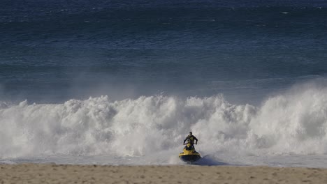 Jet-ski-escaping-big-ocean-wave-in-Nazare,-Portugal,-getting-away-from-danger-water