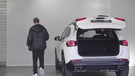 Slow-motion-shot-of-a-young-man-closing-the-boot-on-his-new-Mercedes-Benz-SUV