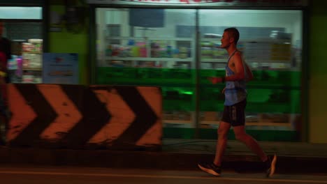 Solo-runner-in-the-Samui-Run-on-Koh-Samui-island,-Malaysia,-being-cheered-and-applaud