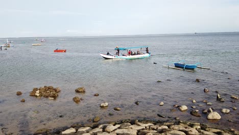 Pescadores,-Barcos-De-Marineros-Que-Llegan-A-La-Playa-De-Sanur-Bali-Indonesia,-Horizonte-Azul-De-Aguas-Tranquilas,-Muelle-De-Piedra-En-Un-Hermoso-Destino-De-Viaje-Pacífico,-Asia