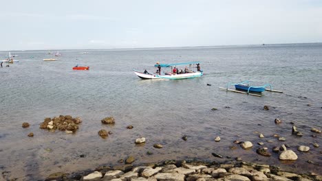 Fishermen,-Sailors-Boat-arriving-at-Sanur-Beach-Bali-Indonesia,-Calm-Sea-Water-Blue-Skyline,-Stone-Dock-in-Beautiful-Peaceful-Travel-Destination,-Asia