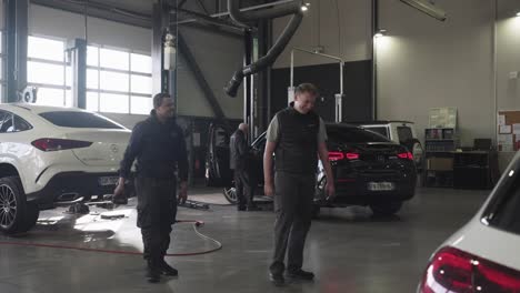 Slow-motion-shot-of-Mercedes-Benz-technicians-passing-a-drill-to-each-other-and-laughing