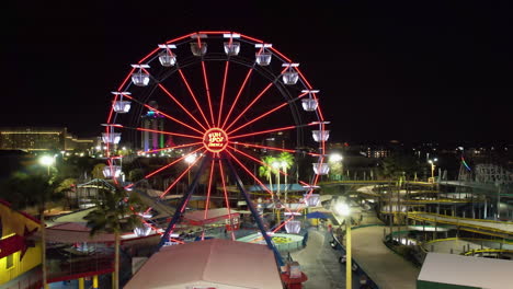 Aerial-view-of-a-illuminated-ferris-wheel-at-a-amusement-park-in-Orlando,-Florida---tracking,-drone-shot