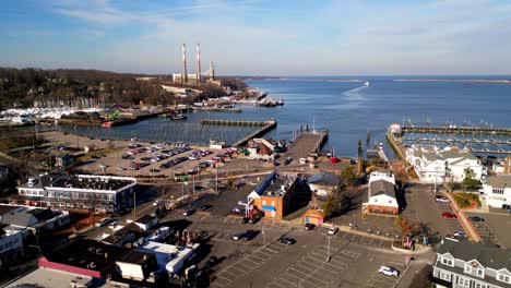 Slight-Overview-Orbit-drone-footage-of-lower-port-jefferson-town-harbor-with-boats,-cars-shops,-buildings,-hotels-in-the-distance