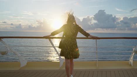 Woman-standing-by-back-of-ship-enjoying-beautiful-sunset
