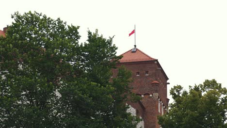 Royal-Wawel-Castle-and-Gothic-Cathedral-in-Krakow,-Poland,-With-Sandomierska-and-Senatorska-Towers,-Polish-Flag-Waving-on-the-Tower