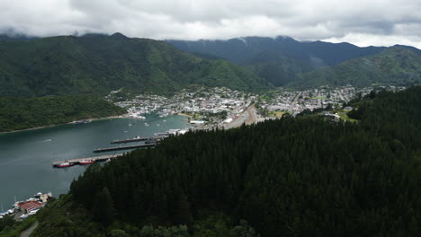 Picton-township-and-harbor-surrounded-by-forest-covered-mountains,-aerial-view