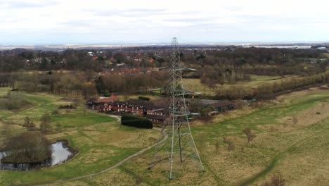 Aerial-orbit-view-across-Electricity-distribution-power-pylon-overlooking-British-parkland-countryside