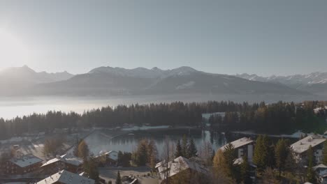 Rotating-aerial-over-alpine-houses-at-lake-of-beautiful-mountain-resort-Crans-Montana,-Switzerland