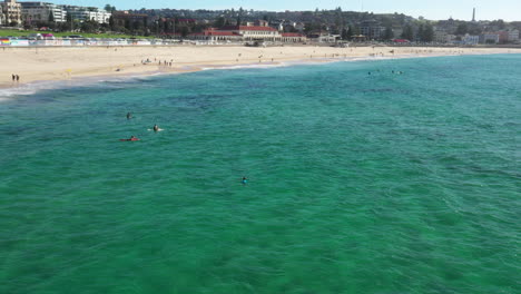 Drone-tracking-around-swimmer-and-surfers-at-Bondi-Beach,-Sydney-Australia