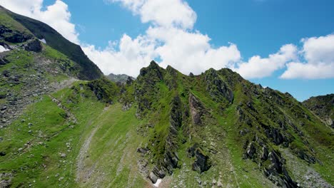 Luftaufnahme-Einer-Wunderschönen-Berglandschaft-Mit-Hohen-Gipfeln,-Dicken,-Flauschigen-Wolken-Und-Einem-Wunderschönen-Grünen-Tal,-Karpaten,-Transfagarasan-Straße-Siebenbürgen,-Rumänien