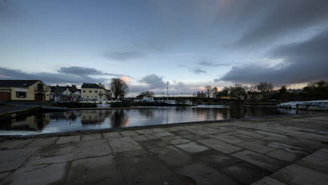 Tag-zu-Nacht-Zeitraffer-Zum-Heiligen-Gral-Von-Carrick-In-Der-Stadt-Shannon-In-Der-Grafschaft-Leitrim-Und-Roscommon-Mit-Verkehr,-Menschen-Und-Ziehenden-Abendwolken-Auf-Dem-Fluss-Shannon-In-Irland