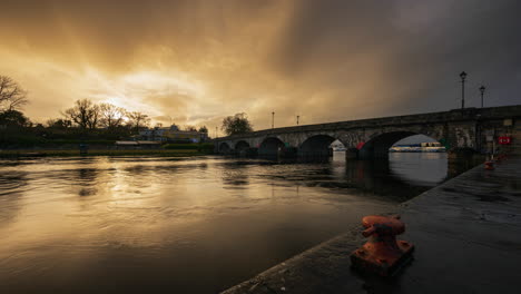 Zeitraffer-Von-Carrick-Auf-Der-Shannon-Town-Bridge-In-Der-Grafschaft-Leitrim-Und-Roscommon-Mit-Verkehr,-Menschen-Und-Bewegten-Regenwolken-Bei-Sonnenuntergang-Am-Abend-Am-Fluss-Shannon-In-Irland