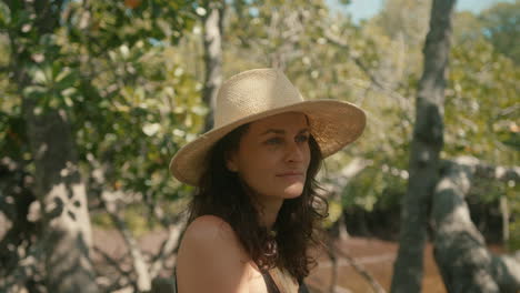 Slow-motion-close-up-of-a-happy-brunette-European-woman-with-a-straw-hat-looking-at-a-green-forest