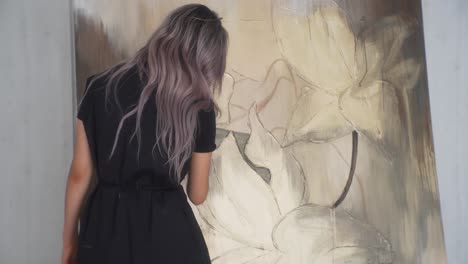 Long-haired-female-artist-painting-on-canvas-in-back-static-view