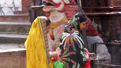 Two-Nepalese-Women-In-Colorful-Head-Veil-Standing-Near-The-Burning-Candles-In-Durbar-Square,-Kathmandu,-Nepal