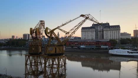 Aerial-parallax-shot-of-two-old-port-cranes-and-Ministry-of-Defense-building-on-background-in-Buenos-Aires