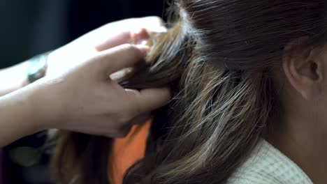 Young-bride-client-sitting-as-hairdresser-brushing-and-styling-hair-in-preparation-for-wedding-ceremony