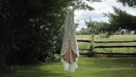 Beautiful-designer-wedding-gown-swaying-in-the-breeze-as-it-hangs-from-a-pine-tree-in-the-back-yard-at-the-Strathmere-Wedding-and-Event-Centre
