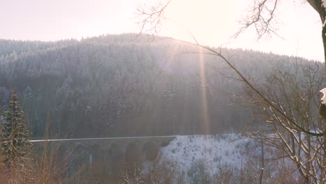 Wintersonne-Scheint-Auf-Ein-Verschneites-Gebirgstal-Mit-Einem-Steinviadukt