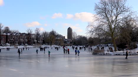 Dutch-authentic-winter-scenery-of-people-on-frozen-canal-ice-skating-in-city-environment-with-barren-trees-and-white-snow-in-cold-cozy-landscape