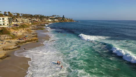 People-Going-Into-The-Ocean-To-Swim-With-Rushing-Waves-In-La-Jolla,-California,-USA
