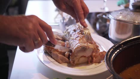Close-up-on-man's-hands,-cutting-chicken-roll-at-home,-orbital-move