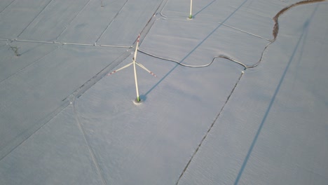 Aerial-View-Of-Wind-Turbines-On-Snow-Covered-Farm-Fields-Of-Northern-Poland-In-Europe---drone-shot