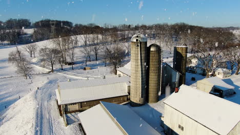 AERIAL-Flyover-Rural-Farm-And-Silo-Towers-During-Snowfall