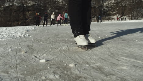 Woman-ice-skating-on-frozen-lake-with-many-people-on-sunny-winter-day