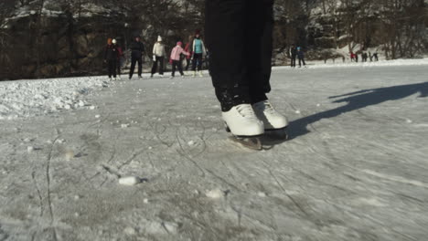 Mujer-Patinando-Sobre-Hielo-En-Un-Lago-Congelado-Con-Mucha-Gente-En-El-Soleado-Día-De-Invierno