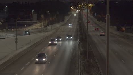 Langsamer-Linksschuss-über-Eine-Stark-Befahrene-Autobahn-Mit-In-Beide-Richtungen-Fahrenden-Fahrzeugen,-Verschneiter-Winterabend