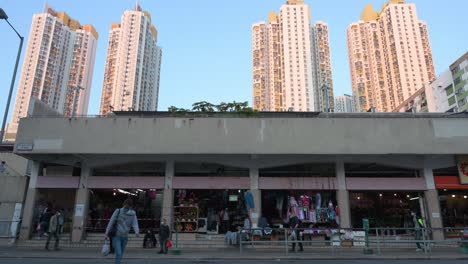 Eine-Frau-überquert-Die-Straße,-Während-Im-Hintergrund-Ein-Sozialwohnungskomplex-In-Hongkong-Zu-Sehen-Ist