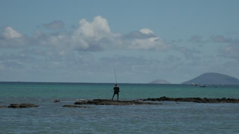 Hombre-Moreno-Mauriciano-Con-Pesca-De-Gran-ángulo-En-Una-Roca-Sobresaliente-Del-Océano-Pacífico