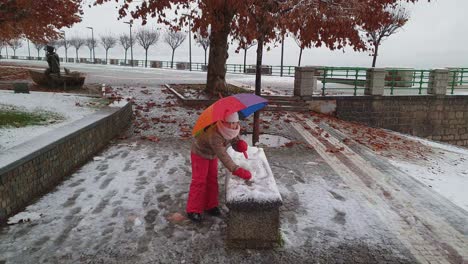 Kindermädchen-Mit-Buntem-Regenschirm-Spielt-Draußen-Schneeball