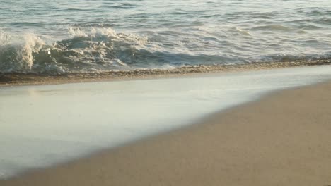 Schönes-Detail-Einiger-Kleiner-Wellen-An-Einem-Strandufer-Bei-Sonnenuntergang