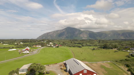 Aerial-shot-flying-over-a-farm-surrounded-by-mountains-and-fields-in-Norway
