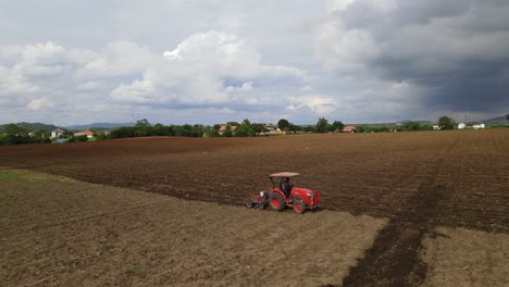 Toma-Estática-De-Un-Tractor-Rojo-Labrando-Un-Rico-Suelo-Fértil,-Moviéndose-En-Diagonal-Dejando-Surcos-Que-Contrastan-Entre-La-Tierra-Arada-Antigua-Y-La-Nueva-En-El-Campo-Rural-De-Tailandia,-Sudeste-De-Asia