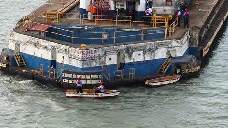 Arbeiter-Des-Panamakanals-Bringen-Die-Festmacherleinen-In-Einem-Kleinen-Ruderboot-Zum-Schiff