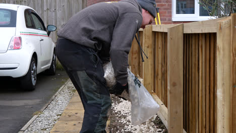 Landscape-gardener-applying-stones-to-the-borders-of-the-newly-fitted-fence