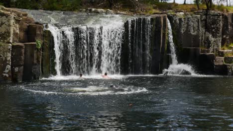 Tracking-shot-of-man-jumping-into-water-at-KeriKeri-Waterfalls-during-summer-day-in-New-Zealand
