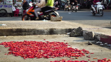 Red-hot-chili-pepper-lies-and-dries-along-the-asphalt-road-on-which-the-scooter-driving,-Vietnam