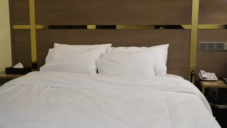 Double-bed-and-white-linen-and-pillows-in-a-typical-hotel-or-guest-room---panning-view