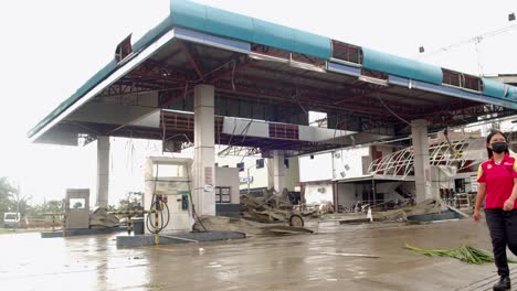 Zerstörte-Tankstelle-Auf-Den-Philippinen-Nach-Taifun-Rai,-Frau-Geht-Vorbei