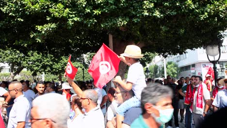 Child-On-His-Father's-Shoulder-Waving-Flag-Of-Tunisia-During-Protest-In-Tunis-City